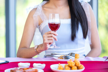 Valentine's day concept, Asian young girl sitting at a table food with wine glasses and bouquet of red and pink roses wine and waiting for her man at in the restaurant background