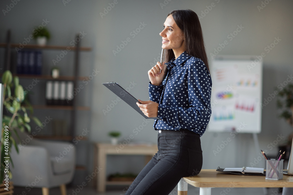 Wall mural Profile side photo of minded charming young woman hold pen face clipboard think idea plan work in office indoors workplace