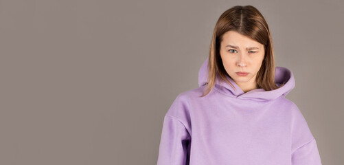 Puzzled beautiful woman with dark eyes biting her lower lip looking with surprise into camera. Human face expressions and emotions. European woman posing in gray studio