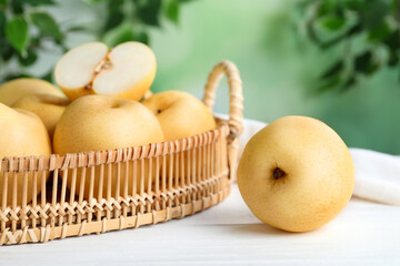 Cut and whole apple pears on white wooden table against blurred background, closeup