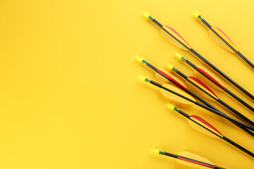 Many arrows and space for text on yellow background, flat lay. Archery sport equipment