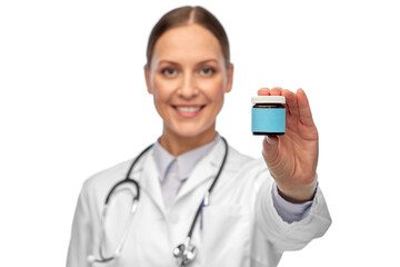 medicine and healthcare concept - close up of happy smiling female doctor with stethoscope holding jar of pills over white background