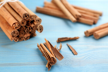 Aromatic cinnamon sticks on light blue wooden table, closeup