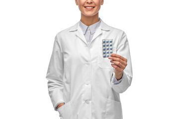 medicine, profession and healthcare concept - happy smiling female doctor in white coat holding pills over white background