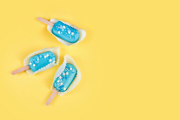 Blue mint ice cream popsicles on yellow background. Tasty and refreshing ice cream on sticks. Minimal summer concept. Flat lay, copyspace for text.