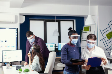 African entrepreneur sharing creative ideas and opinion to coworkers wearing face mask as safety...