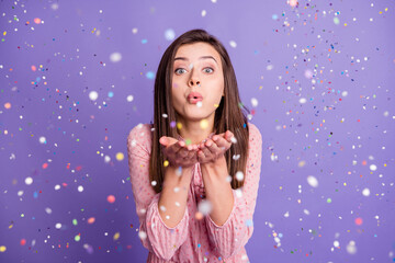 Photo of young attractive girl blow confetti you air fly magic miracle isolated over purple color...