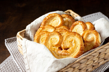 Puff. Flaky sugar Palmiers cookies in a basket on a light background. Sweet homemade cakes	