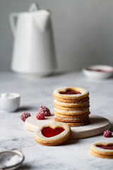 Linzer cookies with hearts stacked on a wooden board