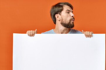 bearded man with poster in hand on orange background Copy Space