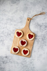 Round cookies with red hearts on a wooden board, top view.