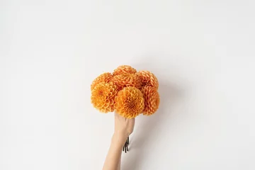Zelfklevend Fotobehang Ginger dahlia flowers bouquet in female hand on white background. Top view, flat lay minimal creative floral concept. © Floral Deco