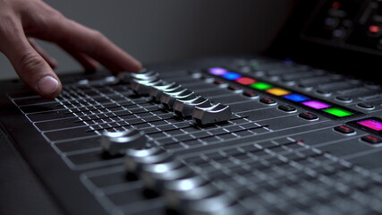 Man works on a professional electronic audio mixer. A control panel for tuning sound channels.