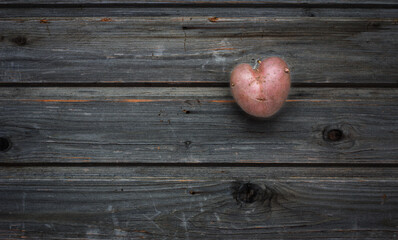 Heart shaped red potato on a gray wooden vintage table in rustic style, valentine day, wooden...
