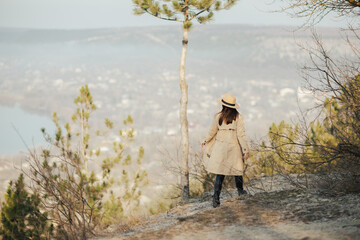 Girl with hat enjoy panorama of town from the hill. Amazing scenic view on town.