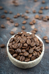 Сoffee beans in a ceramic bowl - selective focus. Scattered coffee beans on a background. High quality photo