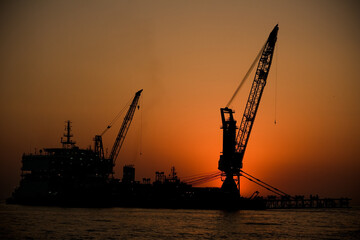 Obraz premium sunset over a crane in the ocean