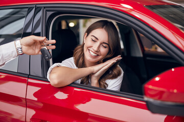Happy woman receiving car keys from dealer