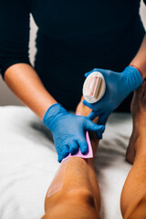 Waxing - Beautician Removing Unwanted Hair from Female Leg with Wax Strips