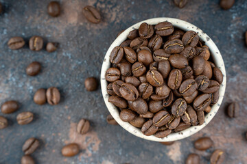 Сoffee beans in a ceramic bowl. selective focus. Scattered coffee beans on a background. Flat lay with copy space. High quality photo