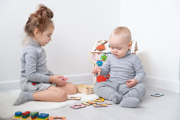 baby boy playing with older sister with wooden toys. early children development.