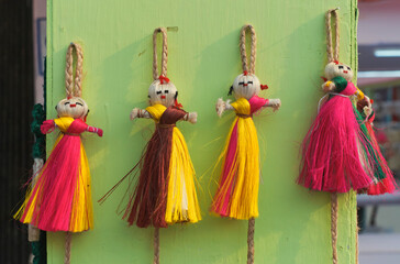Vibrant multicolor jute dolls, used as wall hanging puppets in a retail display for sale at a...