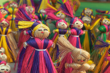 Vibrant multicolor jute dolls, used as wall hanging puppets in a retail display for sale at a...