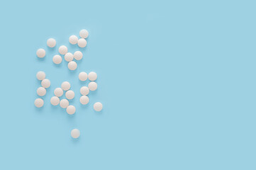 white round pills, pills isolated on blue background. Scattered medicine pills. Healthcare, medical and pharmaceutical concept. copy space