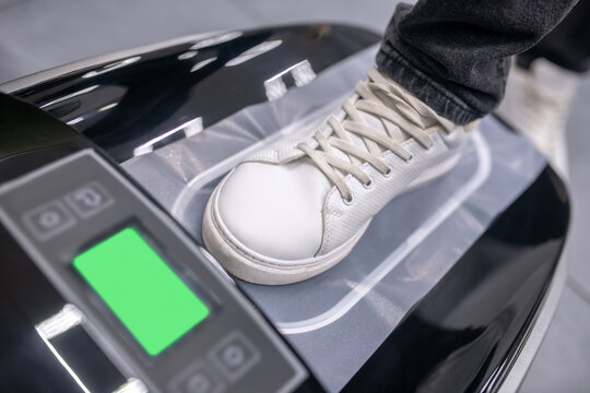 Foot in sneaker on electronic device with thermal film