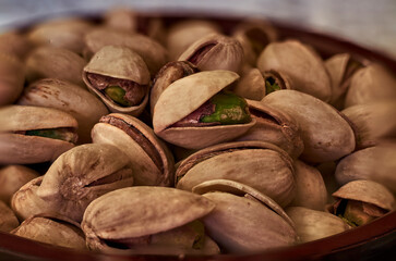 Close-up of green pistachio with open shell, next to more pistachios