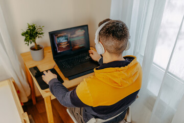 Young man playing computer games in white headphones. Gamer at home. Man working on computer at home.