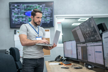 Attentive man with laptop in front of computer monitors