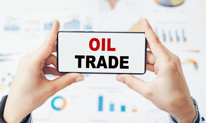 Closeup on businessman holding a smartphone with text OIL TRADE.