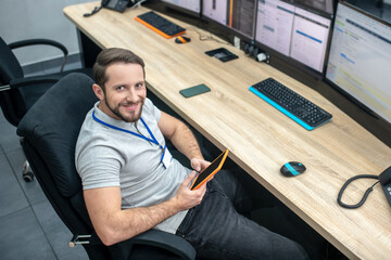 Satisfied man with tablet at workplace during break