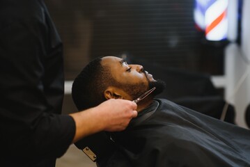 Black man in the barbershop. Cute black man makes a haircut in the African salon. Hair style....