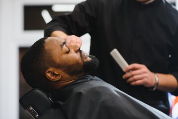 Black man in the barbershop. Cute black man makes a haircut in the African salon. Hair style....