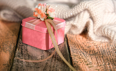 Partial blurred wooden desk table with knitted scarf and pink gift box . Vintage tinted,hygge, cozy home concept.