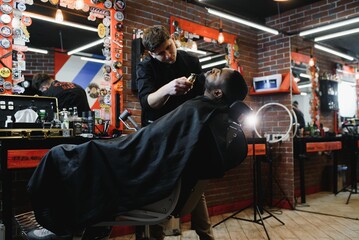 African male client getting haircut at barber shop from professional hairstylist.