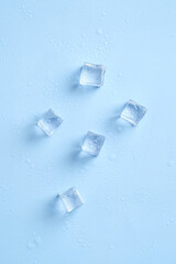 Shiny ice cubes and water drops on blue background. Top view.