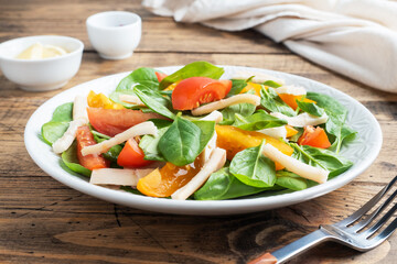 Salad of boiled squid, fresh tomatoes, spinach leaves. Delicious bright diet dish with vegetables and seafood.