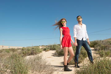 young couple wearing sunglasses enjoying the beach and stroll