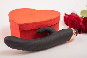Black dildo and heart shaped box and red roses on a white background. Valentine's day gift.