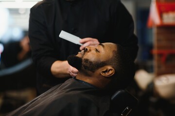Black man in the barbershop. Cute black man makes a haircut in the African salon. Hair style. Haircut for adults.