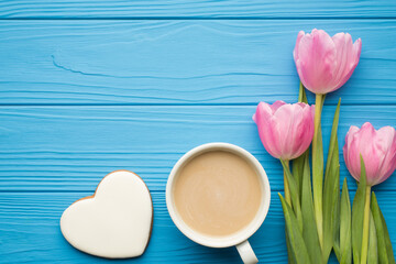 Flat lay photo picture of three pastel color tulips cup of tasty latte and gingerbread cookies on bright color blue table