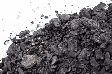 Coarse coal in the snow in winter. Maintaining high temperatures in fuel boilers, home heating...