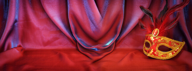 Photo of elegant and delicate Venetian mask over red silk background