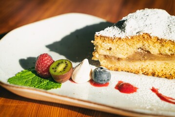 Apple pie on a plate decorated with fruits. Sweet dessert with apple, strawberry and fruits