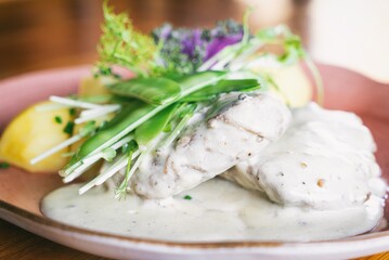 Pork tenderloin in wine with green pepper, vegetables and potatoes on a plante. Dinner main dish on a wooden table. Traditional polish cuisine