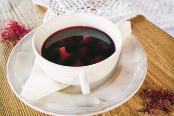 Red borscht with dumplings or a croquette on a plante. Dinner soup on a wooden table. Traditional polish cuisine