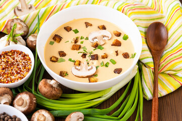 Mushroom soup with onions, garlic and pepper on a wooden table.